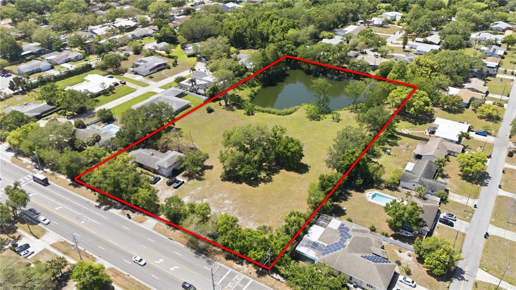 An aerial view shows a large, rectangular lot with a pond and a house — 1276 S BELCHER ROAD, CLEARWATER, FL