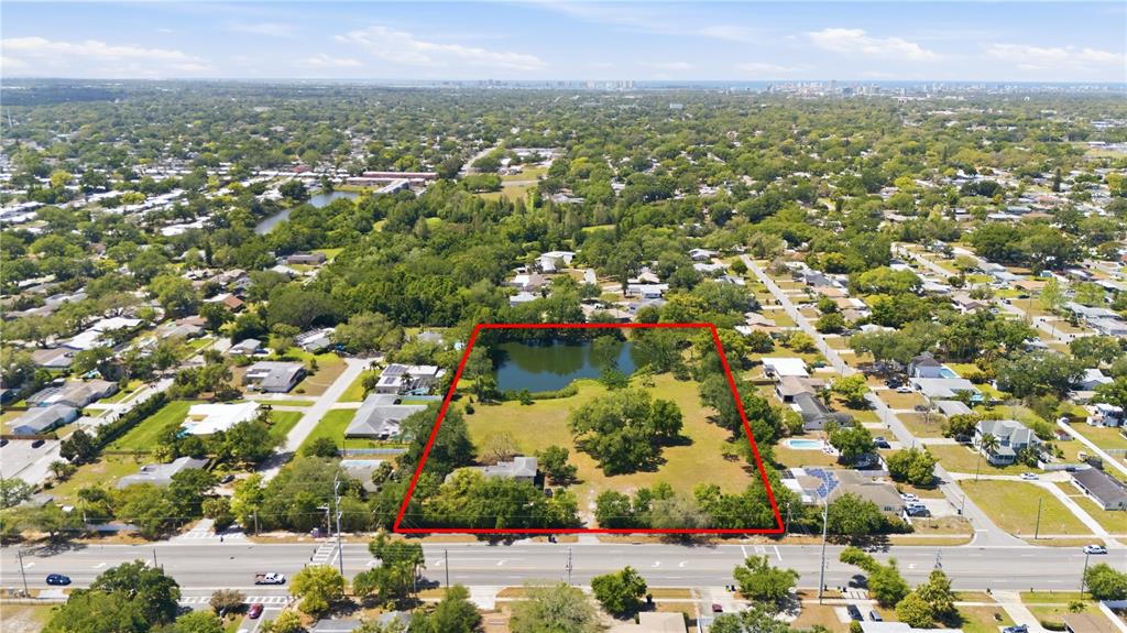 An aerial view shows a large, rectangular lot with a pond and trees — 1276 S BELCHER ROAD, CLEARWATER, FL