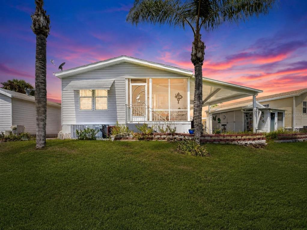 A single-story mobile home with a screened front porch, palm trees, and a grassy lawn — 370 CITRUS RIDGE DRIVE, DAVENPORT, FL