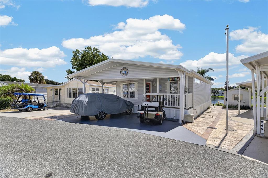 A light-colored mobile home features a covered carport, a golf cart, and a paved driveway — 370 CITRUS RIDGE DRIVE, DAVENPORT, FL