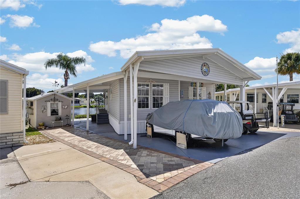 A light-colored manufactured home with a covered carport and a small detached shed — 370 CITRUS RIDGE DRIVE, DAVENPORT, FL