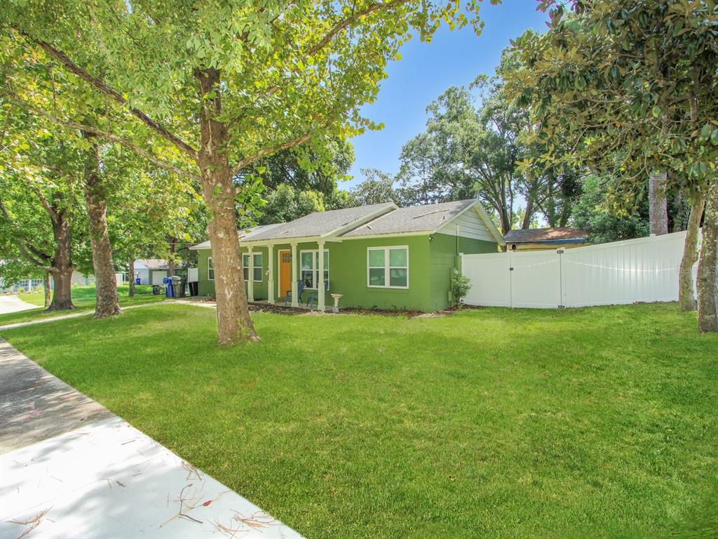 A green house with a white fence stands on a grassy lawn under large trees — 2011 NANCY ANN TERRACE, OCOEE, FL