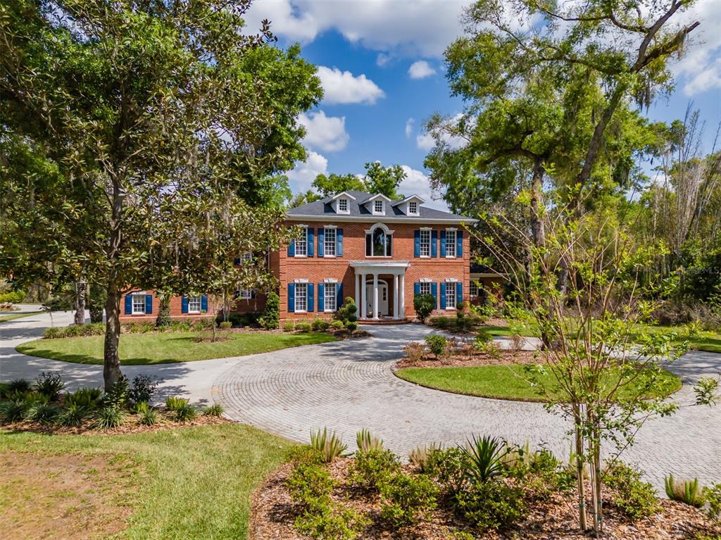 A two-story brick house with blue shutters and a circular paver driveway — 1816 S DOVER ROAD, DOVER, FL