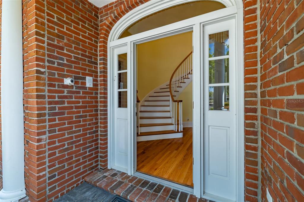A brick exterior entryway leads into a foyer featuring a curved wooden staircase — 1816 S DOVER ROAD, DOVER, FL