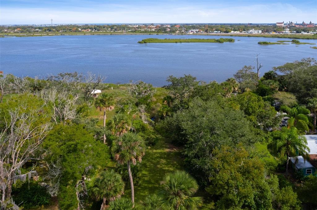 An aerial view shows a grassy clearing surrounded by trees leading to a large lake — 29 & 27A FLORIDA AVENUE, ST AUGUSTINE, FL