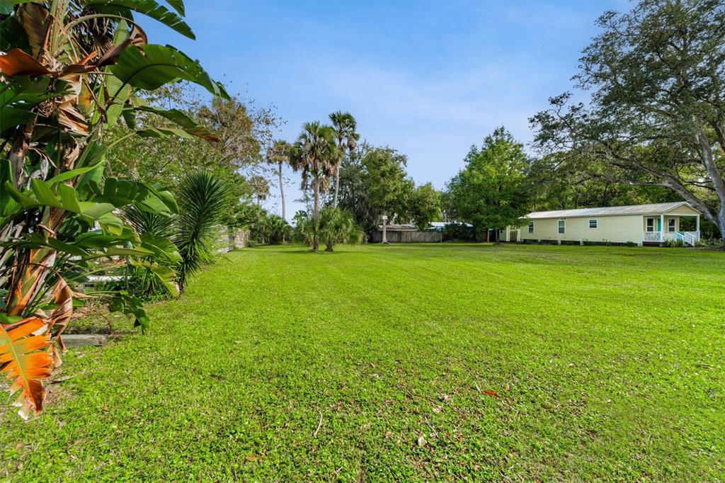 A large, grassy backyard features palm trees, mature oaks, and a light-colored mobile home — 29 & 27A FLORIDA AVENUE, ST AUGUSTINE, FL