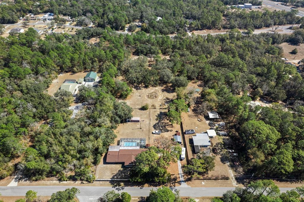 An aerial view shows two residential properties with pools and outbuildings surrounded by dense forest — 265 S THAYER AVENUE, LECANTO, FL