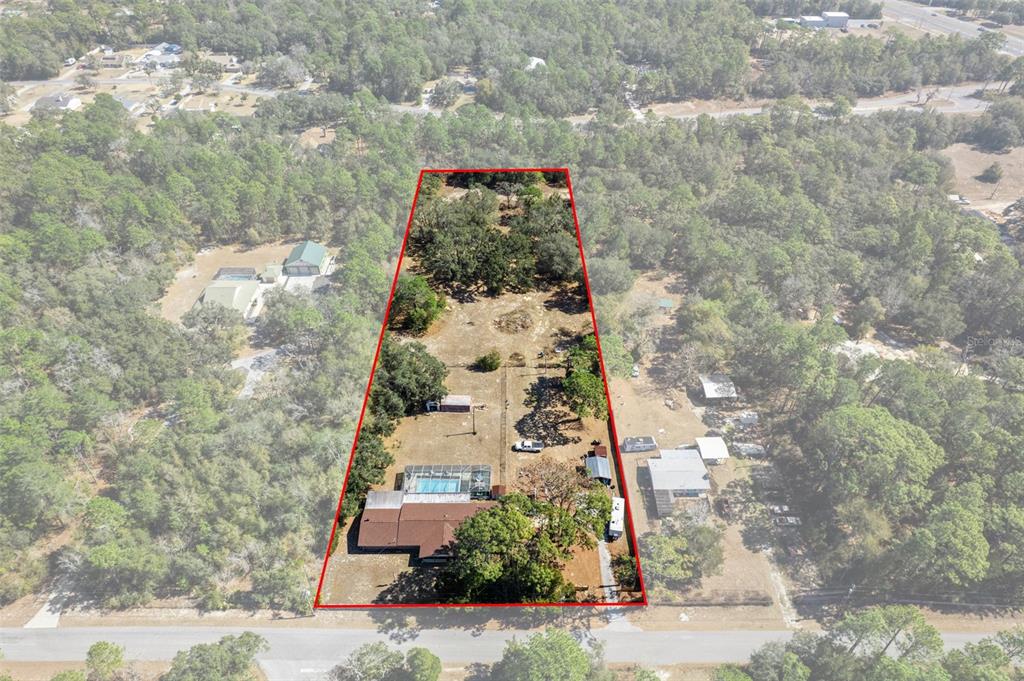 Aerial view of a house with a pool on a large, wooded rectangular lot — 265 S THAYER AVENUE, LECANTO, FL