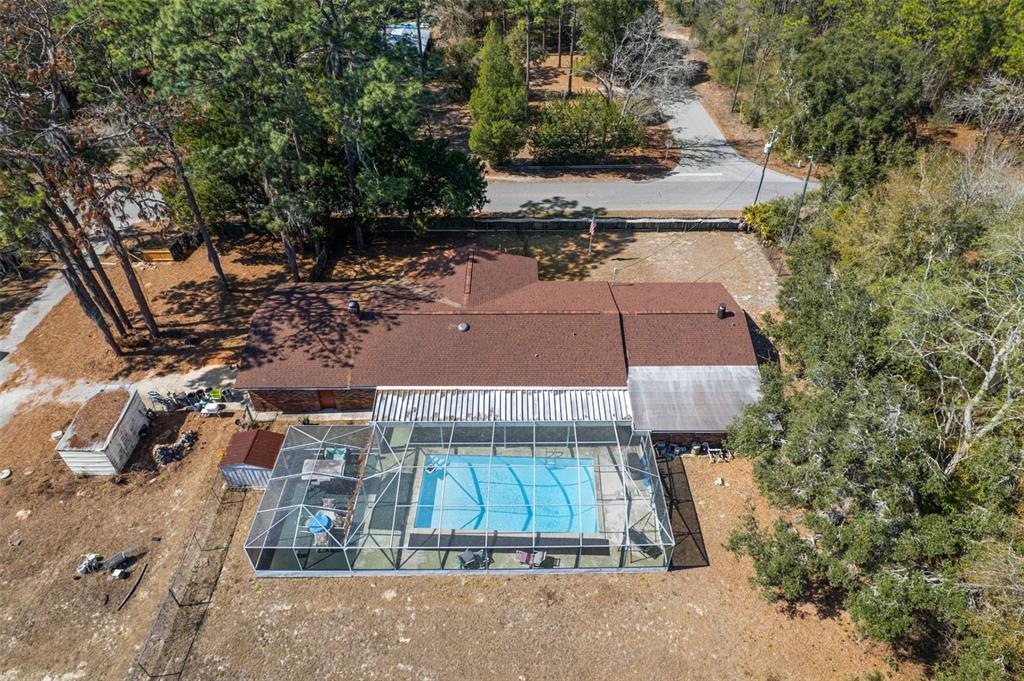 An aerial view shows a house with a brown roof and a screened-in swimming pool — 265 S THAYER AVENUE, LECANTO, FL