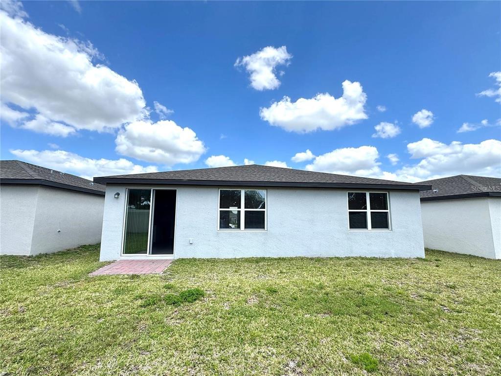 The rear exterior of a single-story house features a sliding glass door and two windows — 3024 CASSIDY LANE, HAINES CITY, FL