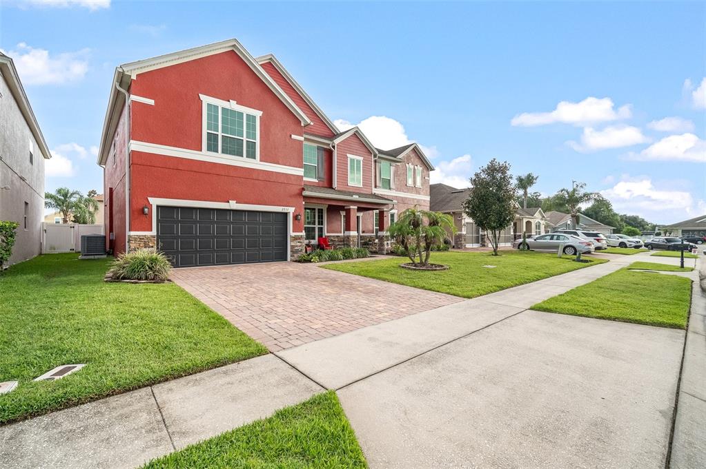 A two-story red house with a brick driveway and a two-car garage — 2711 CYPRESS TREE TRAIL, ST CLOUD, FL