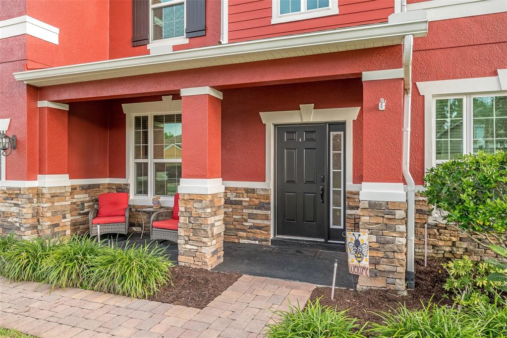 A red house with a stone-accented porch, black front door, and two outdoor chairs — 2711 CYPRESS TREE TRAIL, ST CLOUD, FL