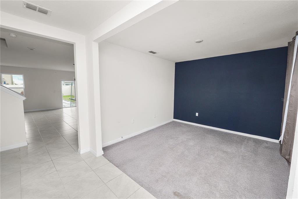 A room with gray carpet and a dark blue accent wall adjacent to a tiled area — 3935 PALAZZO PLACE, WINTER HAVEN, FL