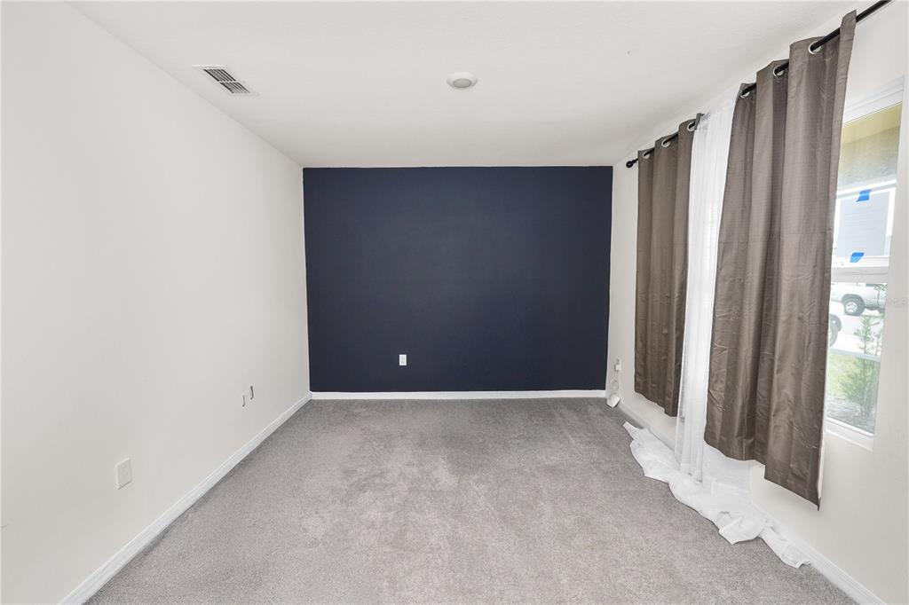A bedroom features gray carpeting, white walls, a dark blue accent wall, and window curtains — 3935 PALAZZO PLACE, WINTER HAVEN, FL