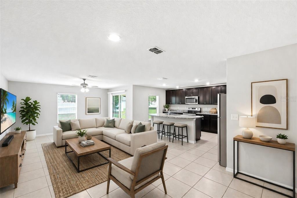 An open-concept living room and kitchen with light tile floors and dark wood cabinetry — 1668 GOPHER TREE STREET, MASCOTTE, FL