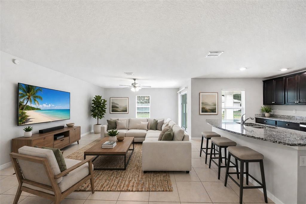 A living room and kitchen area with light tile floors, a sectional sofa, and island seating — 1668 GOPHER TREE STREET, MASCOTTE, FL