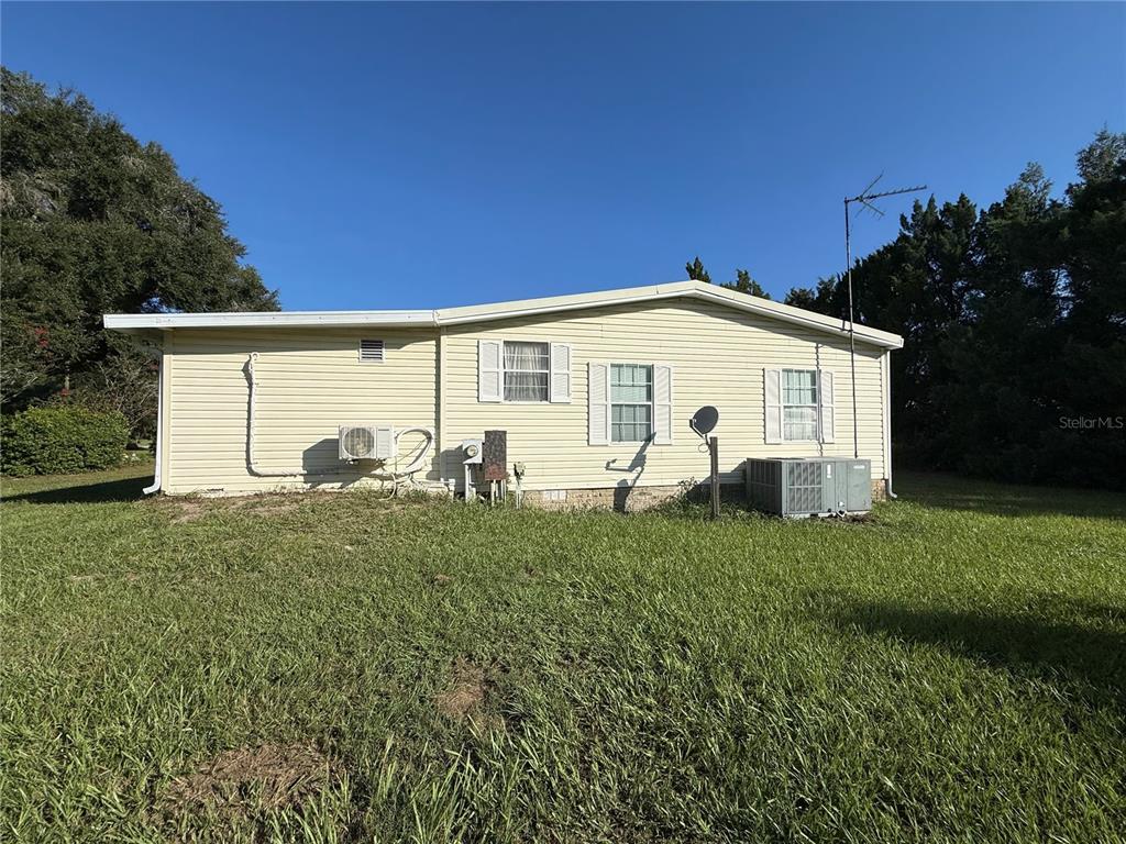 The exterior of a light yellow manufactured home sits on a grassy lot — 8285 COUNTY ROAD 109B, LADY LAKE, FL