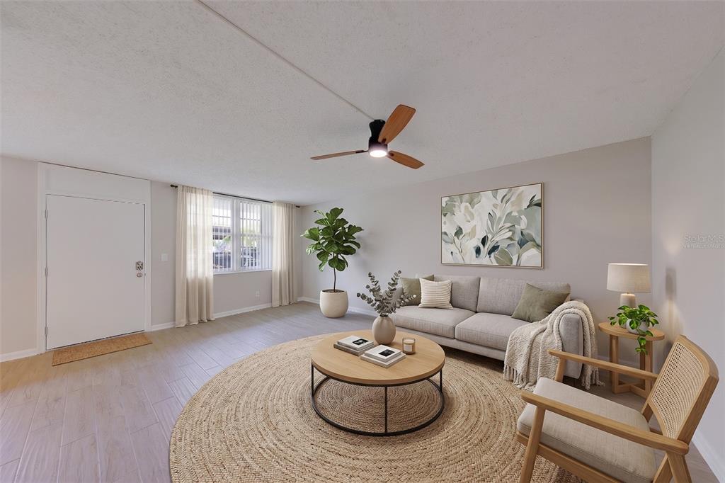 A living room features a round jute rug, a grey sofa, and a ceiling fan — 4715 BAY STREET NE UNIT 132, ST PETERSBURG, FL