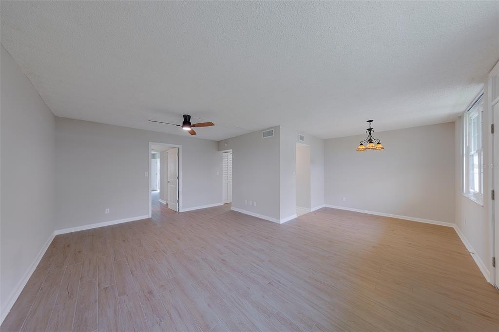 An open-concept living and dining area with light wood-look tile flooring and a ceiling fan — 4715 BAY STREET NE UNIT 132, ST PETERSBURG, FL