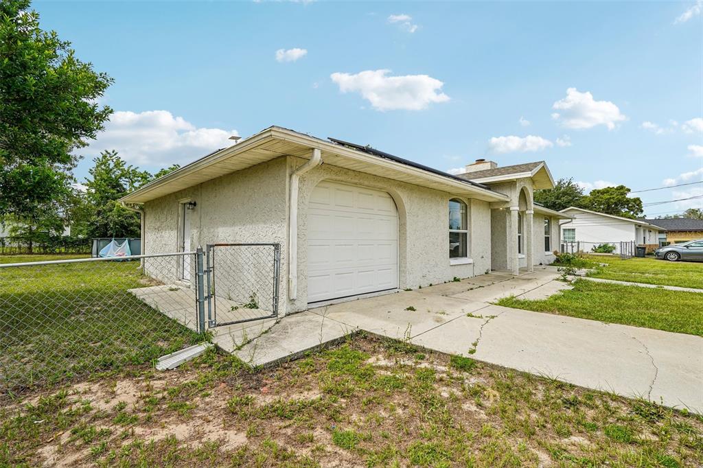 A single-story house with a stucco exterior, a one-car garage, and a chain-link fence — 18 SPRING RADIAL, OCALA, FL