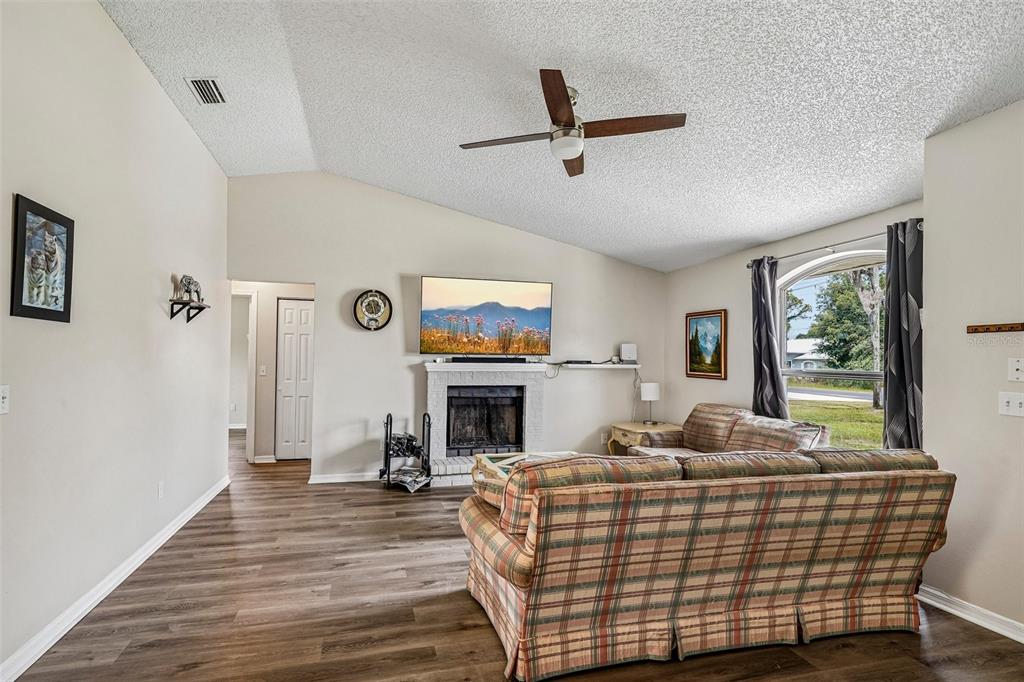 A living room features a fireplace, a television, a ceiling fan, and plaid furniture — 18 SPRING RADIAL, OCALA, FL
