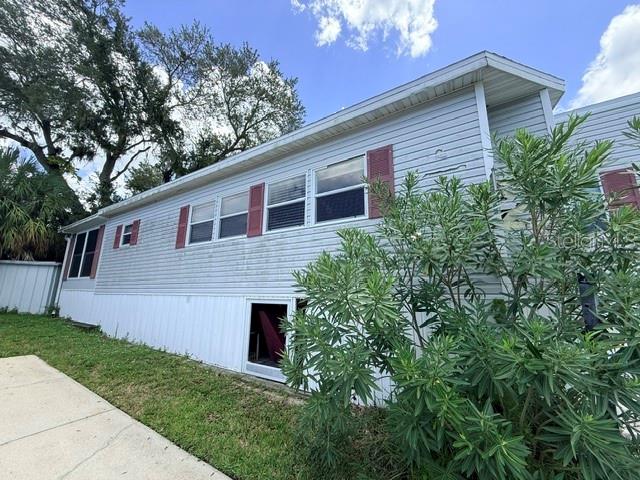 The exterior of a light blue mobile home features vinyl siding and a large green bush — 2215 73RD STREET E UNIT 315, PALMETTO, FL