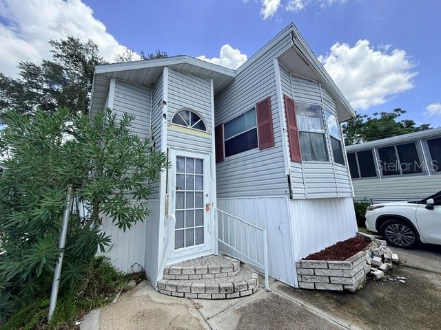 A light gray mobile home with a front entrance, brick steps, and a white car — 2215 73RD STREET E UNIT 315, PALMETTO, FL