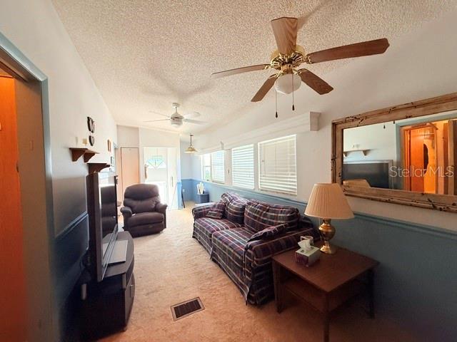A living room features a plaid sofa, a recliner, ceiling fans, and a large wall mirror — 2215 73RD STREET E UNIT 315, PALMETTO, FL