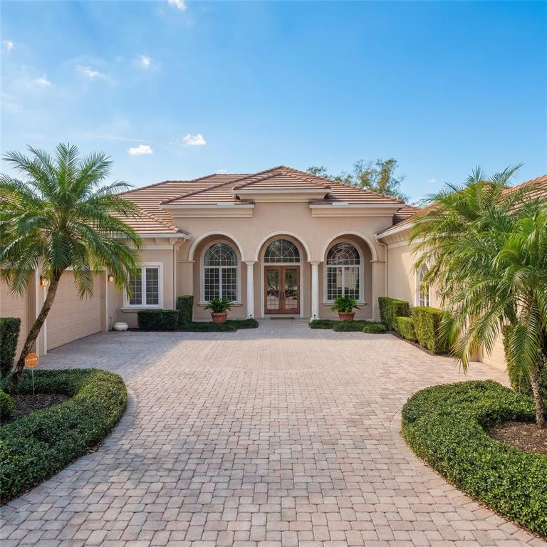 A beige single-story house with a tiled roof, arched windows, and a paved driveway — 5151 LATROBE DR, WINDERMERE, FL