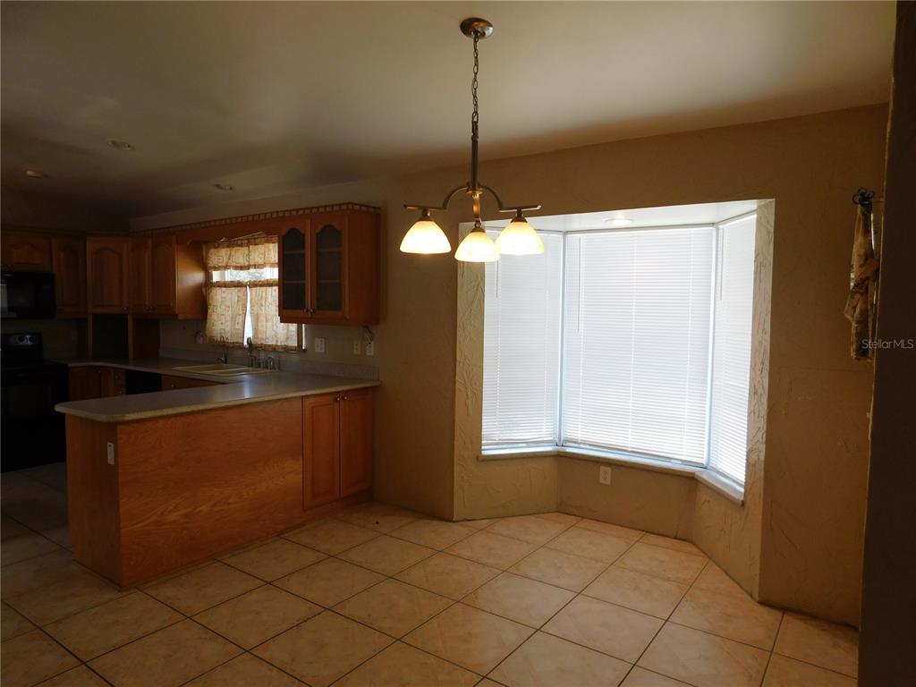 A kitchen and dining area with wood cabinets, tile flooring, and a bay window — 5430 2ND AVENUE N, ST PETERSBURG, FL