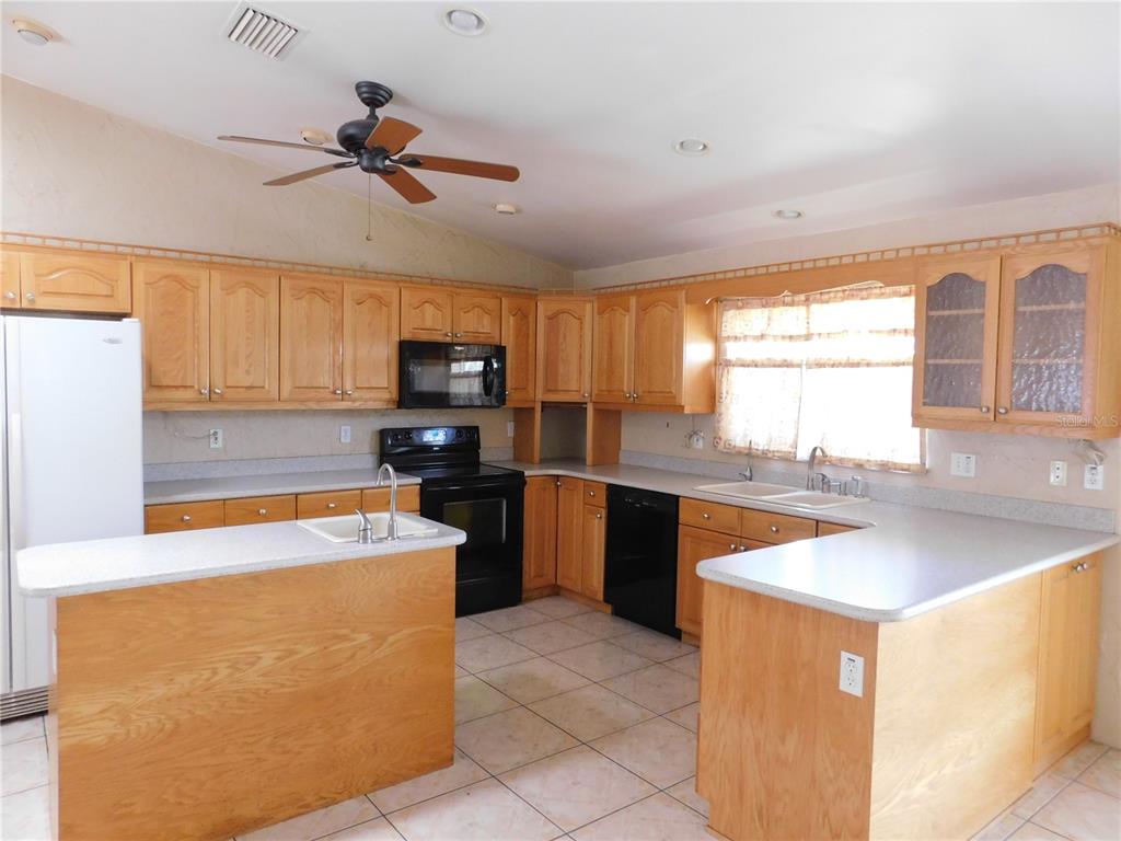 A kitchen features light wood cabinets, black appliances, a central island, and tiled flooring — 5430 2ND AVENUE N, ST PETERSBURG, FL