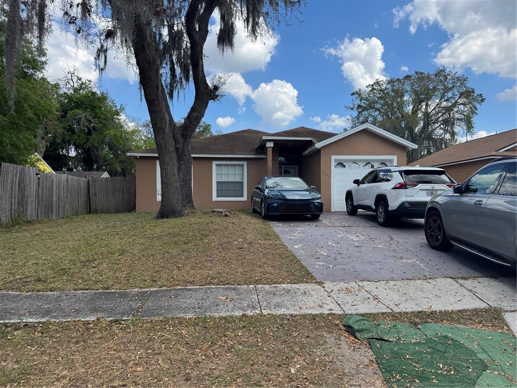 A single-story house with a tan exterior, a driveway, and a large tree in front — 3407 LAKE TINY CIRCLE, ORLANDO, FL