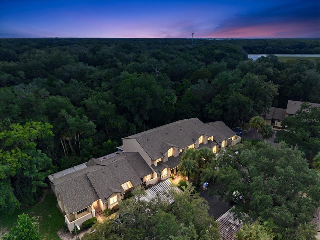 A two-story tan stucco townhouse features a covered carport and a landscaped front yard — 476 CLUB DRIVE, WINTER SPRINGS, FL