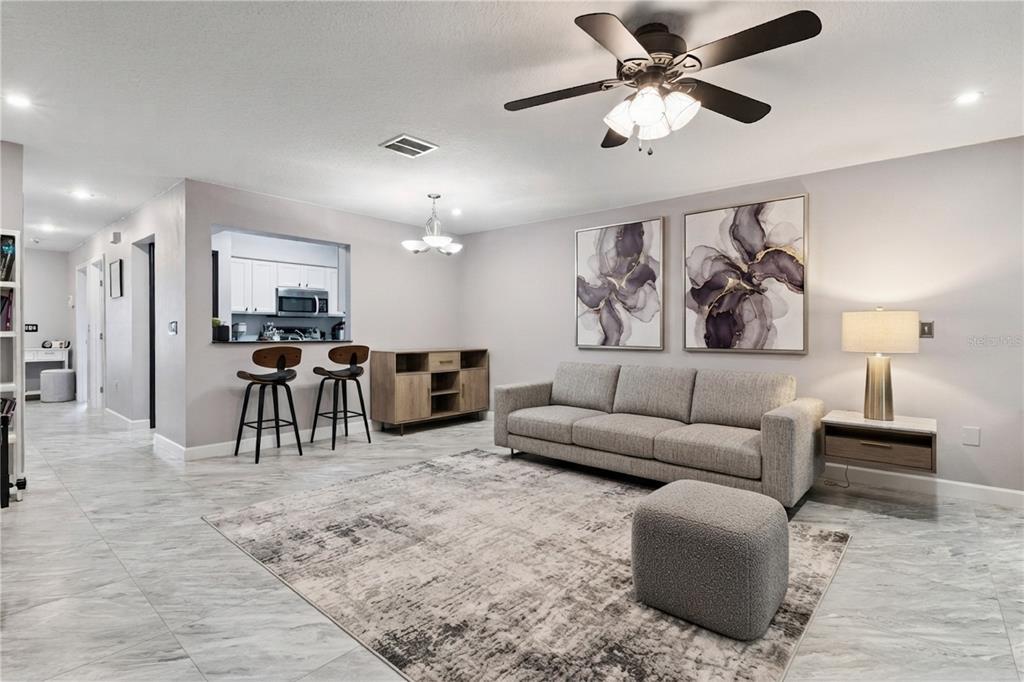 A living room features gray tile floors, a dark sofa, and a breakfast bar area — 476 CLUB DRIVE, WINTER SPRINGS, FL