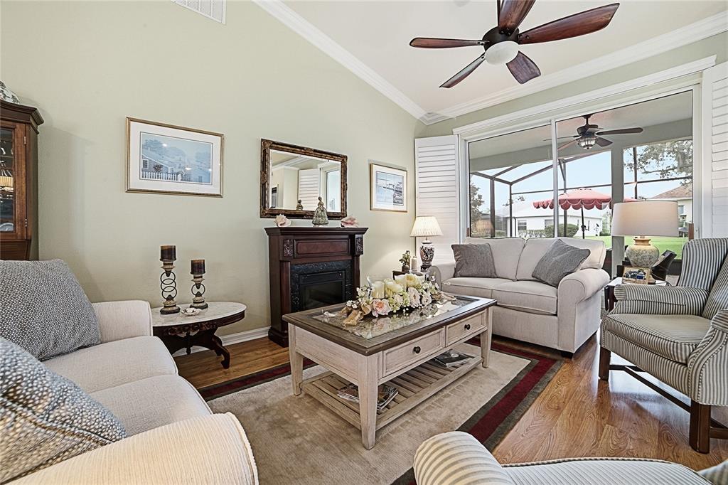 A living room features a fireplace, a coffee table, upholstered seating, and a ceiling fan — 3550 HUNTSVILLE LANE, LEESBURG, FL