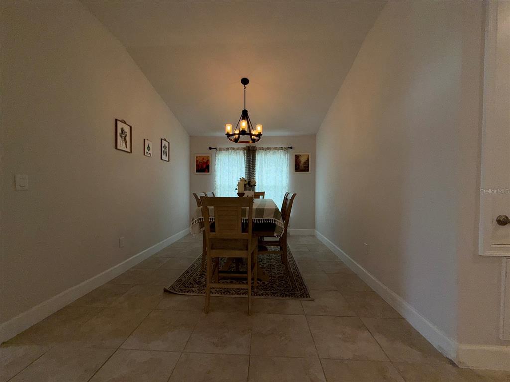 A dining room features a wooden table, chairs, a chandelier, and tile flooring — 14921 TROPICAL VIOLET WAY, WIMAUMA, FL