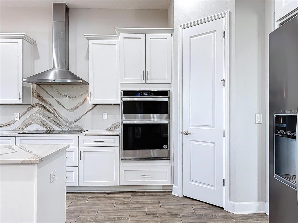 A modern kitchen features white cabinets, stainless steel appliances, and a marble-patterned backsplash — 5216 LAKE VENICE DRIVE, WIMAUMA, FL