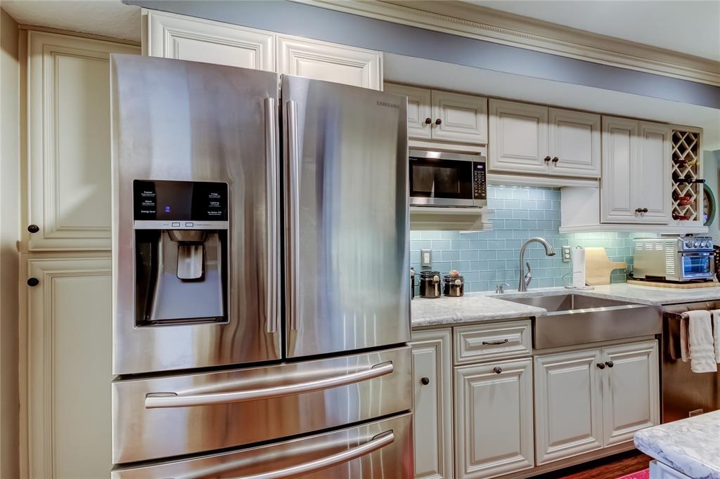 A kitchen features stainless steel appliances, light-colored cabinets, and a blue subway tile backsplash — 433 PAULA DRIVE S UNIT 27, DUNEDIN, FL