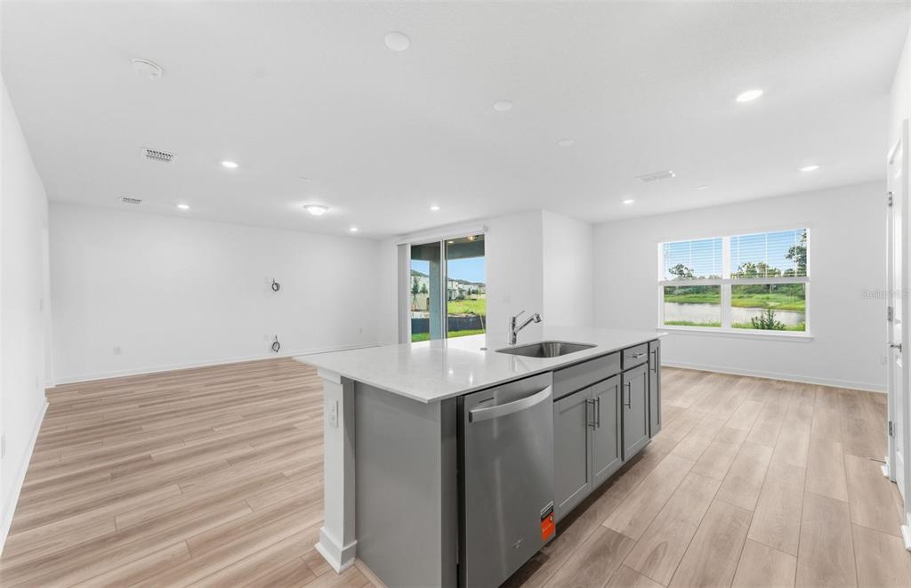 A kitchen with dark wood cabinets, a white island, and an adjacent dining area — 9885 TRELLIS VINE WAY, PARRISH, FL