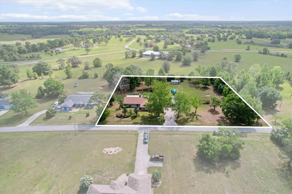 An aerial view shows a house on a large, tree-filled lot with a paved driveway — 8921 S THOROUGHBRED POINT, INVERNESS, FL