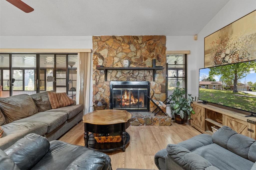 A living room features a stone fireplace, wood flooring, and a television on a wooden console — 8921 S THOROUGHBRED POINT, INVERNESS, FL