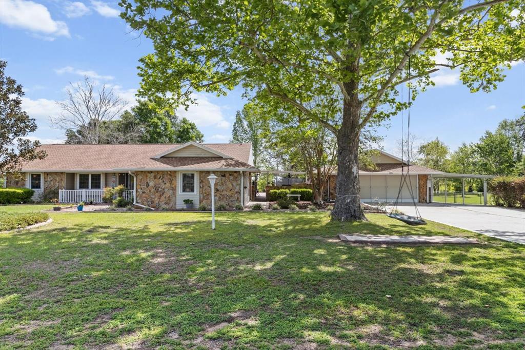 A single-story stone house with a large tree, a tire swing, and an attached garage — 8921 S THOROUGHBRED POINT, INVERNESS, FL