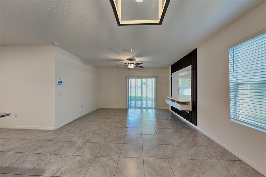 An open living room features tile flooring, a ceiling fan, and a wall-mounted media console — 230 MEGHAN CIRCLE, DELAND, FL