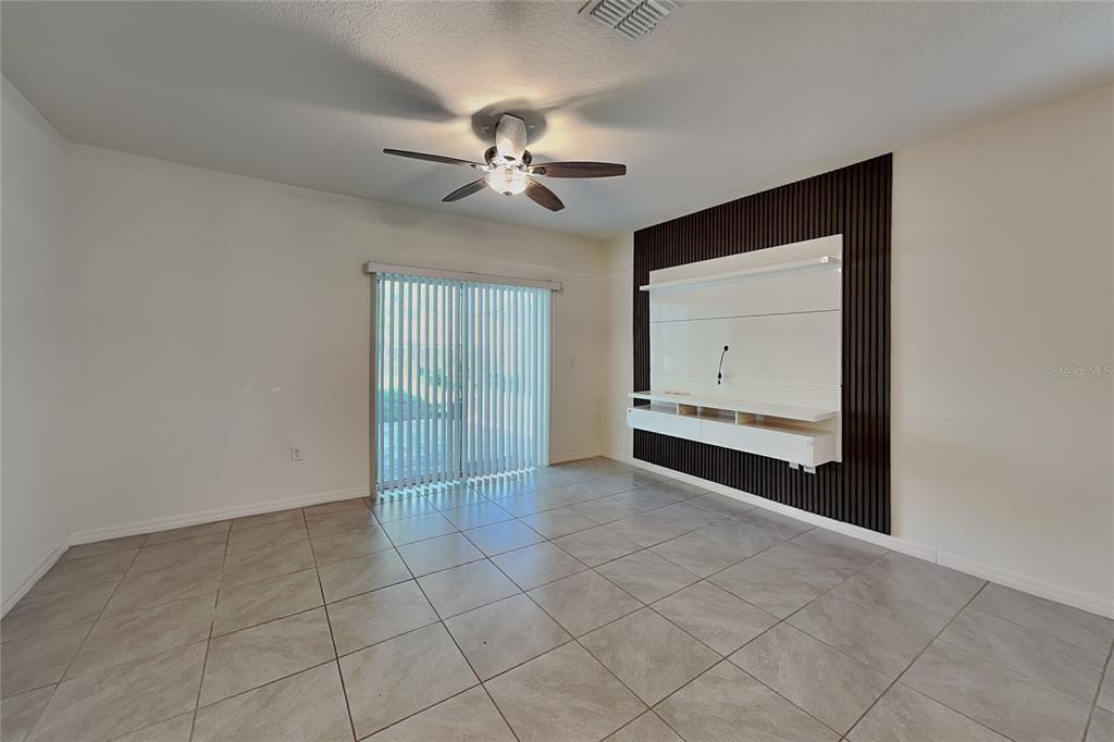 A living room features tile flooring, a ceiling fan, and a wall-mounted media console — 230 MEGHAN CIRCLE, DELAND, FL