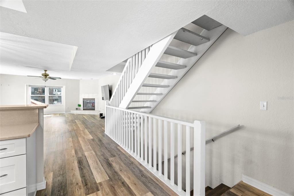 A kitchen with white cabinets and stainless steel appliances overlooks a living area and staircase — 545 PINELLAS BAYWAY S UNIT 207, TIERRA VERDE, FL