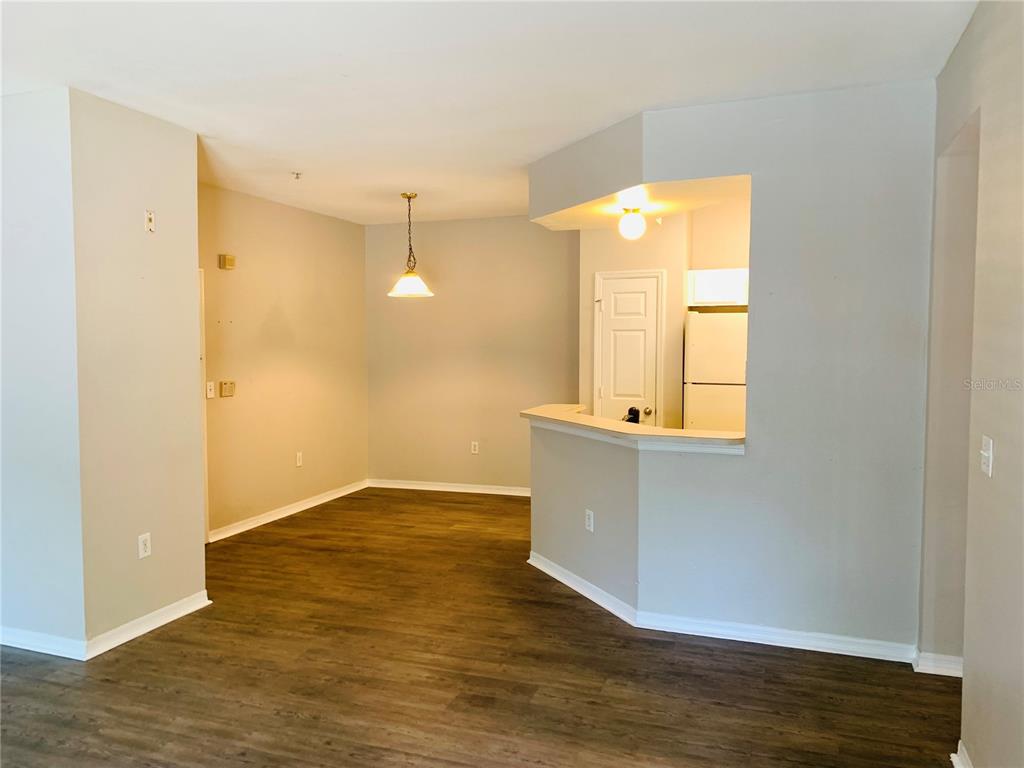 An interior view shows a dining area with wood-look flooring and a kitchen pass-through — 2025 ERVING CIRCLE UNIT 104, OCOEE, FL