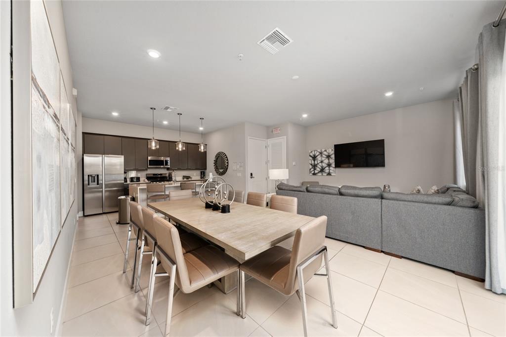A modern living room features a grey sectional sofa, a television, and a glass console — 7740 SANDY RIDGE DRIVE UNIT 131, REUNION, FL