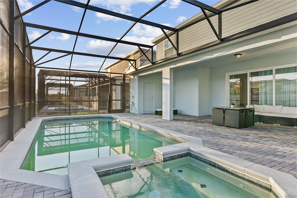 A screened-in patio features a swimming pool, a hot tub, and outdoor furniture — 16208 SAINT MARTIN STREET, CLERMONT, FL