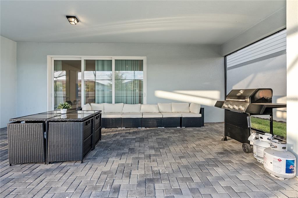 A covered patio features a paved floor, a modular sofa, a dining set, and a grill — 16208 SAINT MARTIN STREET, CLERMONT, FL