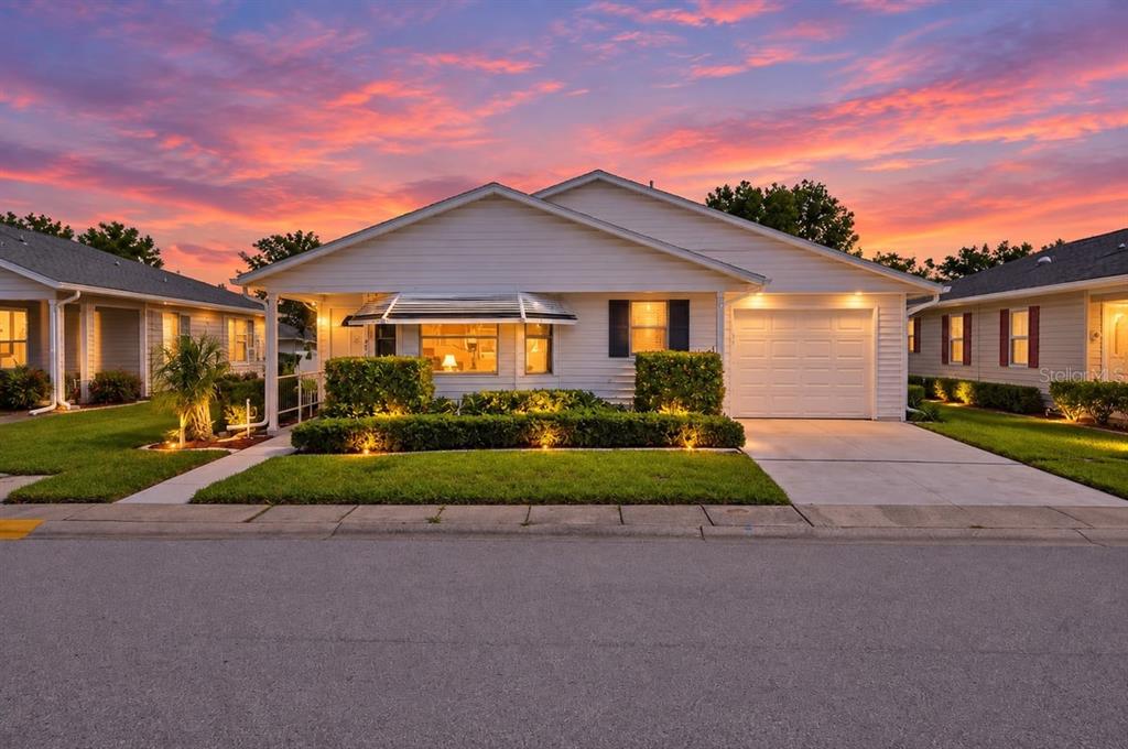 A single-story white house features a front entrance, a small porch, and landscaped bushes — 2033 LONG BOAT DRIVE, LAKELAND, FL